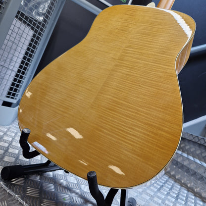 Pre-Owned Yamaha FG840 Close-up of a wooden guitar on a stand with a textured floor background