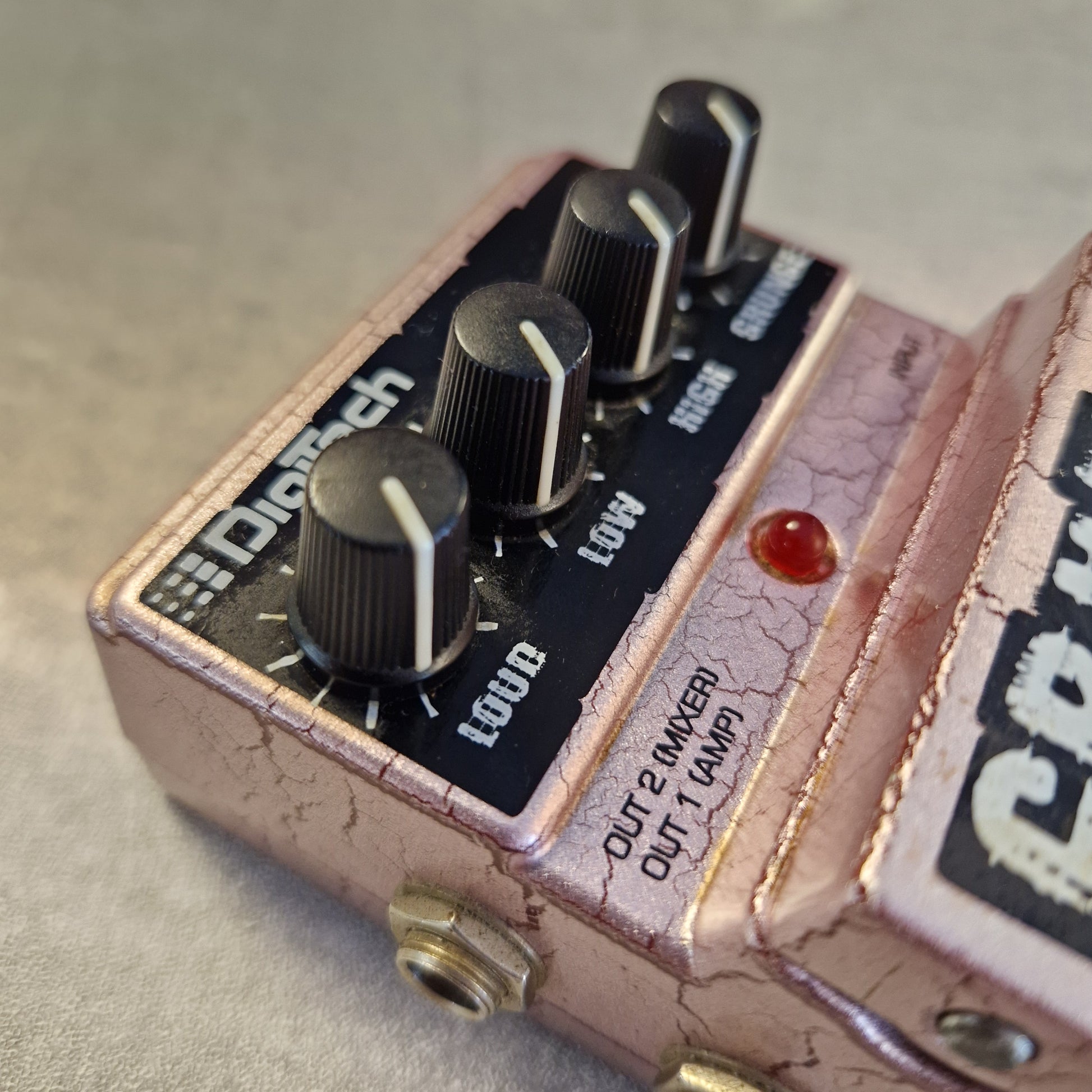 Pre-Owned Digitech Grunge A close-up of a Diaphy distortion guitar pedal with a distressed rose gold finish, black knobs, and a red indicator light.