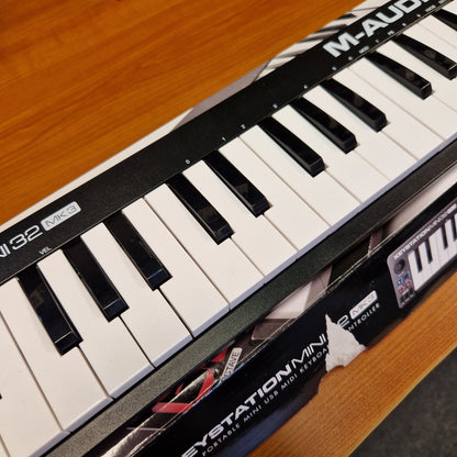 Pre-Owned M-Audio Keystation A close-up diagonal view of a Maudio Synstation 22 synthesizer keyboard, showing black and white keys, the brand name 'MAUDIO' on the black panel, and the Synstation 22 logo on the side.