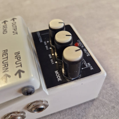 Pre-Owned Boss NS-2  A close-up of a white guitar effects pedal with black knobs and a black control panel. The visible text includes 'CHECK/MUTE', 'REDUCTION', 'MODE', 'MUTE', 'REDUCTION', 'OUTPUT', 'INPUT', and 'RETURN'.