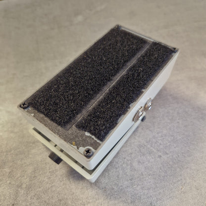 Pre-Owned Boss NS-2  A rectangular white plastic electronic component or enclosure with two large black textured foam or felt panels on the top surface, photographed on a light gray fabric background.