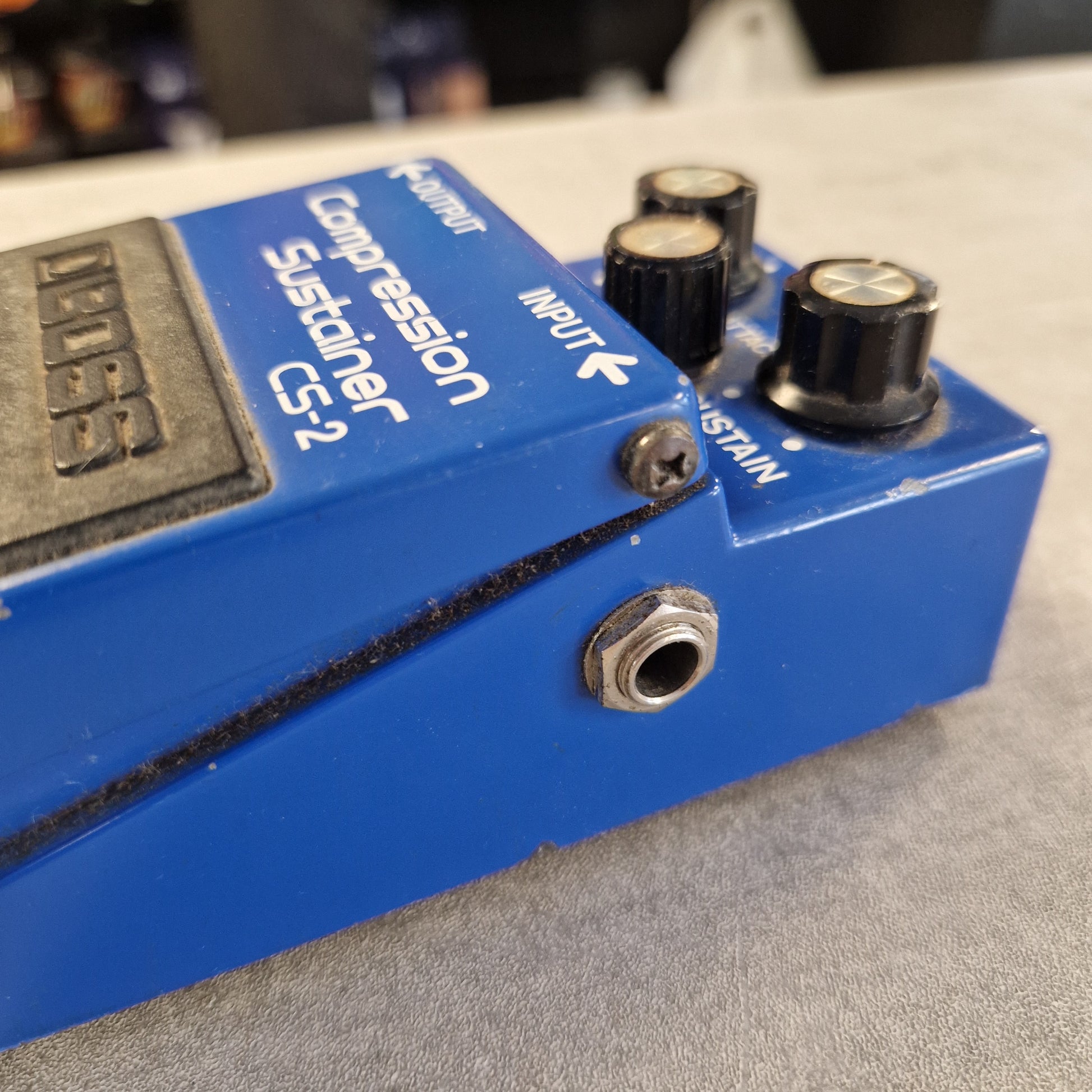 Pre-Owned Boss CS-2 A close-up shot of a blue Looss CS-2 Compression Sustainer pedal against a gray textured background.