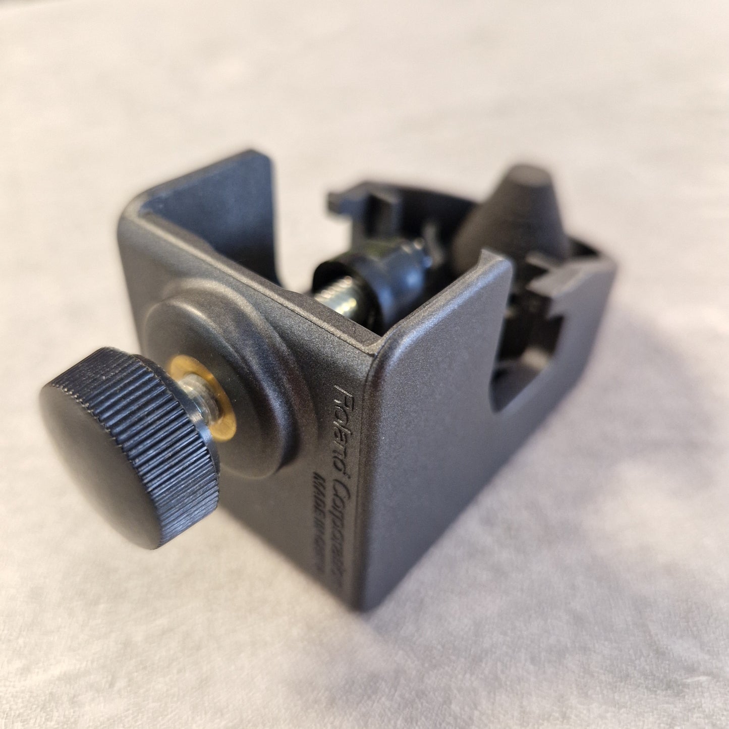 Pre-Owned Roland RT-30H A Roland Corporation black plastic mounting bracket with a textured black adjustment knob and a small gold-colored accent ring, shown on a light gray textured background.