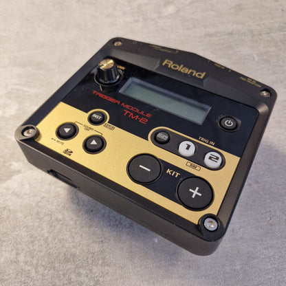 Pre-Owned Roland TM-2  Roland TD-1020 Modulars TME2 digital audio module in black and gold, photographed on a textured gray surface.