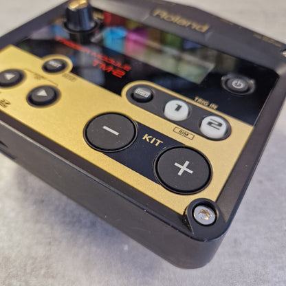 Pre-Owned Roland TM-2 Close-up of a Roland TW2 electronic music controller showing the control panel with gold and black buttons on a gray surface.