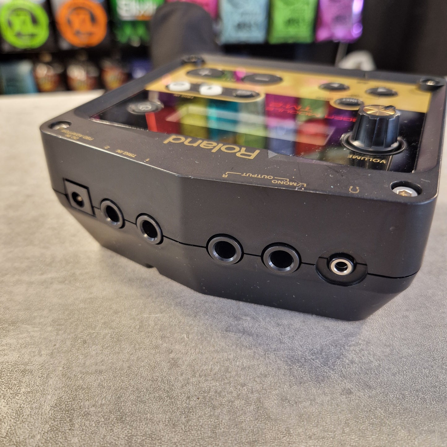 Pre-Owned Roland TM-2 A Roland multi-effects guitar pedal shown at an angle on a gray textured surface, with its colorful internal circuitry visible through a transparent side panel.