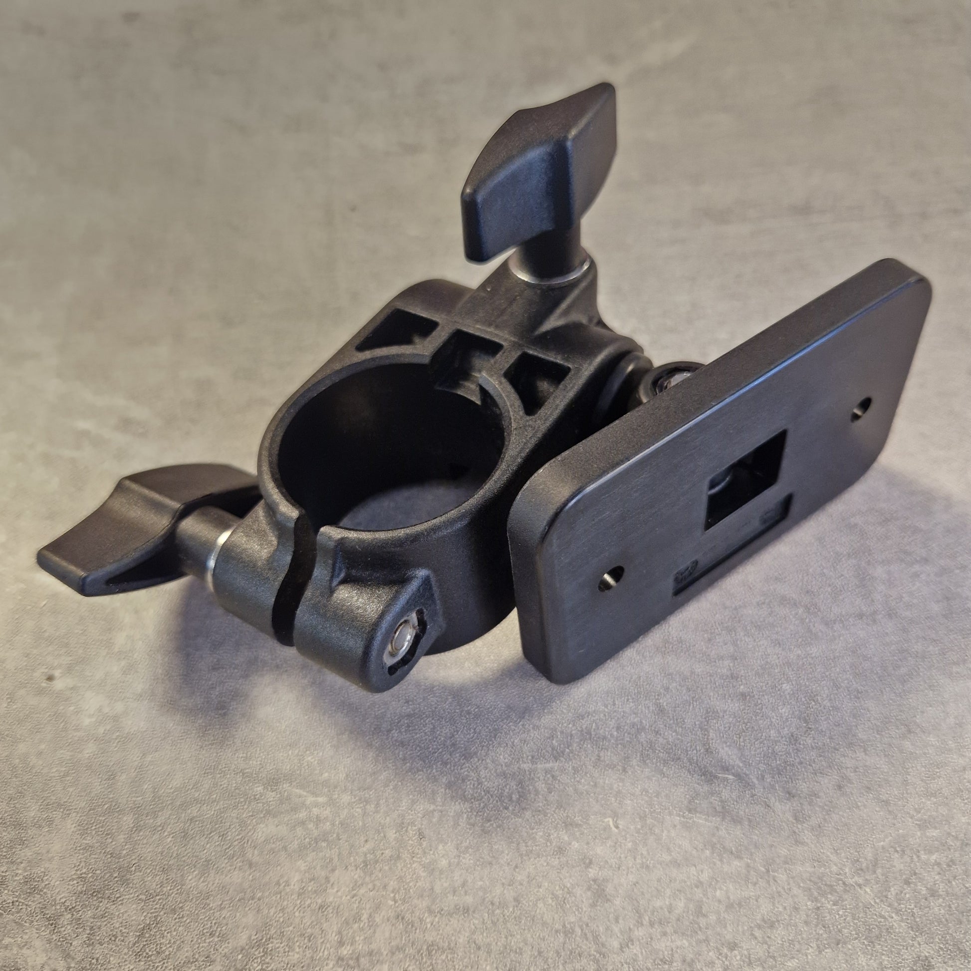 Pre-Owned Roland TM-2 A dark gray metal mounting clamp with a rectangular plate on top and two adjustable wing nuts, photographed against a textured gray background.