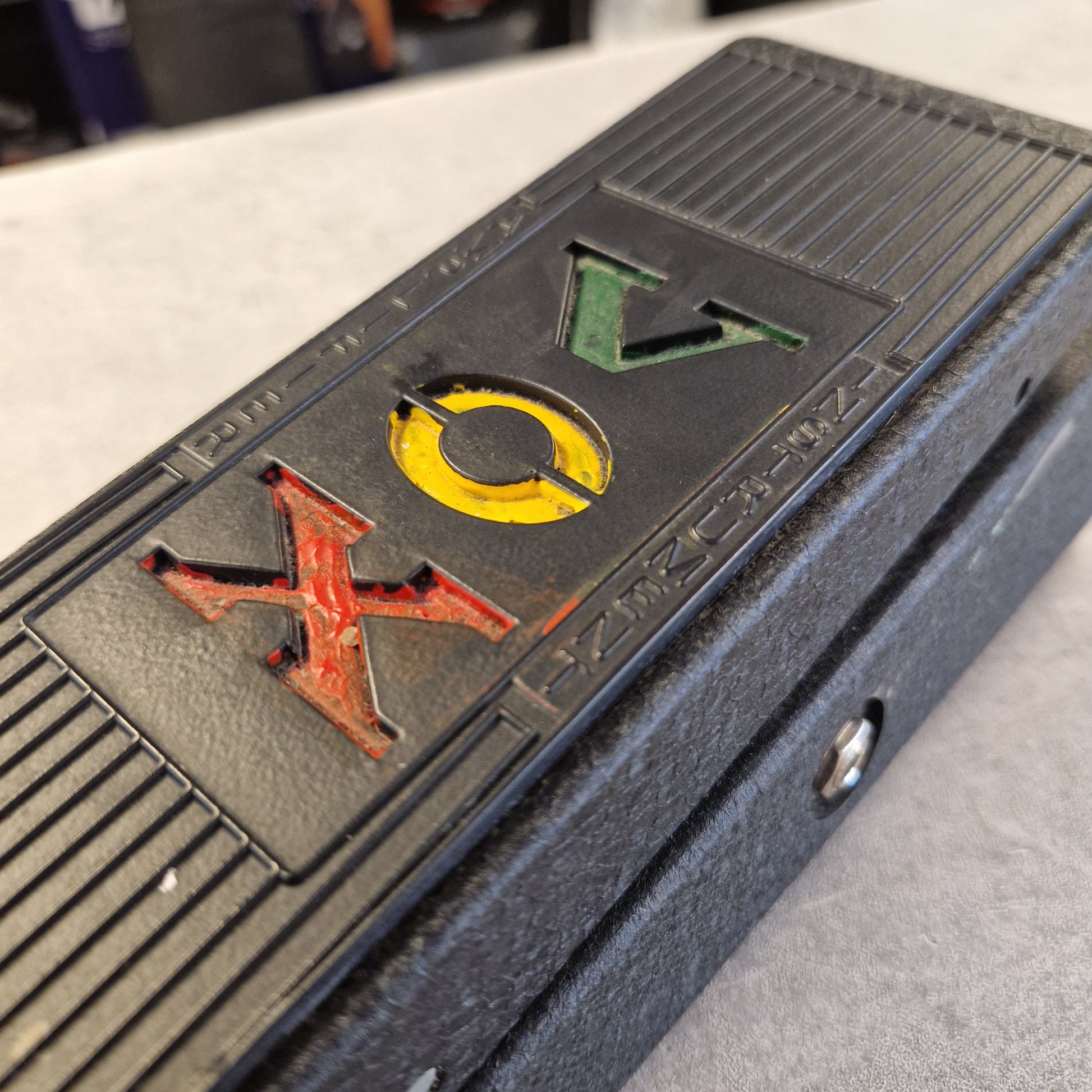 Pre-Owned Vox V845 Close-up of a black textured electronic device with the letters 'VOX' in green, yellow, and red on the front.