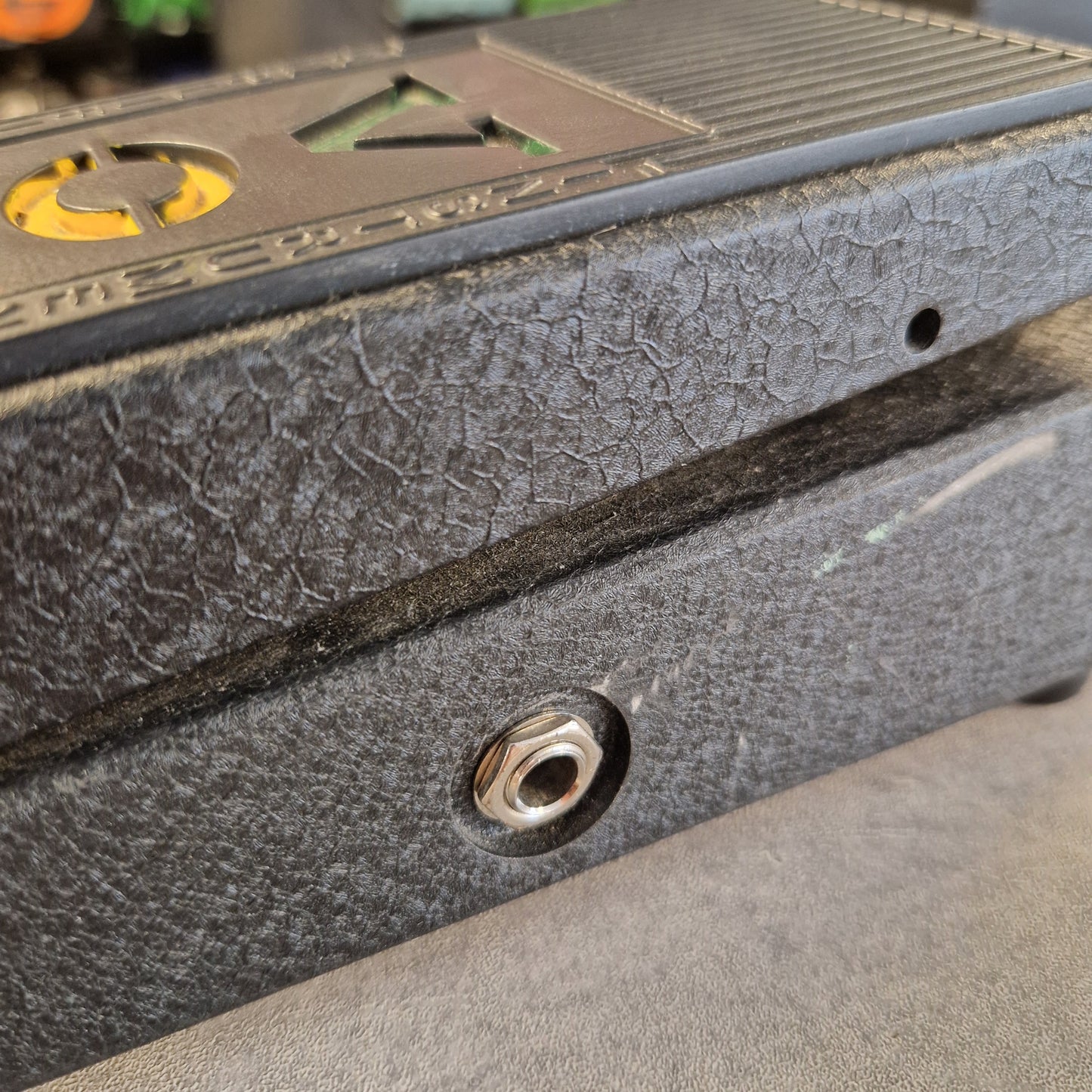 Pre-Owned Vox V845 Close-up detail of a textured black metal surface with a hex screw fastener and part of a yellow-and-black branded panel.