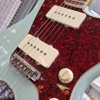 Pre-Owned Fender Close-up of a guitar body showing a red tortoiseshell pickguard, cream humbucker pickups, chrome hardware, and a pale mint green edge.