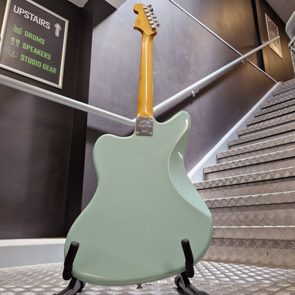 Pre-Owned Fender A mint green electric guitar body with a yellow maple neck, photographed hanging from black display stands in a showroom or studio.
