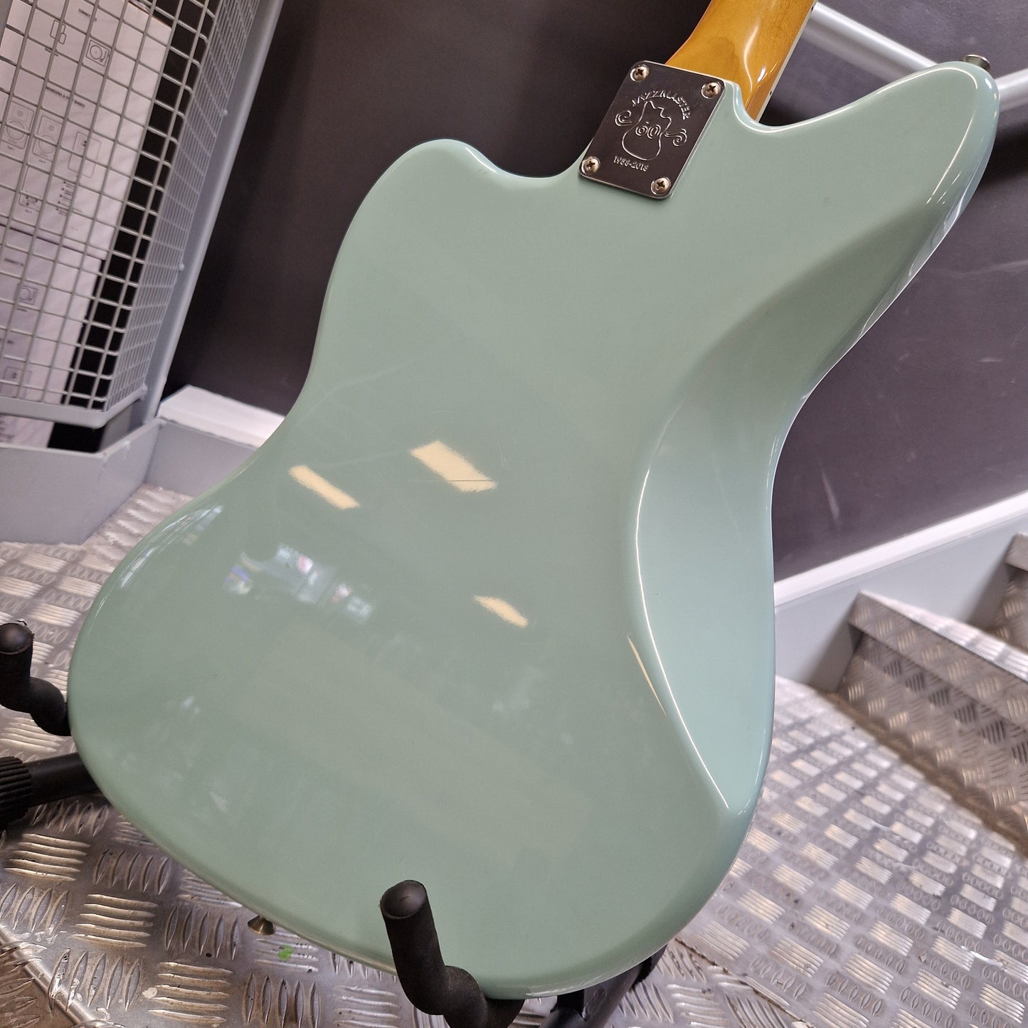 Pre-Owned Fender Close-up of the back side of an electric guitar body in a pale mint green finish, showing part of the yellow neck and a metal plate.