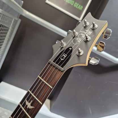 Pre-Owned PRS SE CE24 Close-up of a guitar headstock and upper neck, showing the brand name 'Gibson' and model 'CB' on a dark display background.