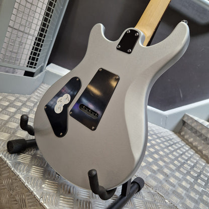 Pre-Owned PRS SE CE24 Silver electric guitar body with black pickguard and hardware, resting on a metal stand on a diamond plate floor.