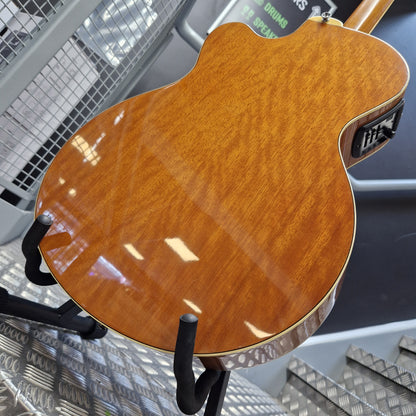 Pre-Owned Yamaha CPX700 Close-up of the glossy back of an electric guitar showing a warm honeyburst wood finish, resting on a black stand.
