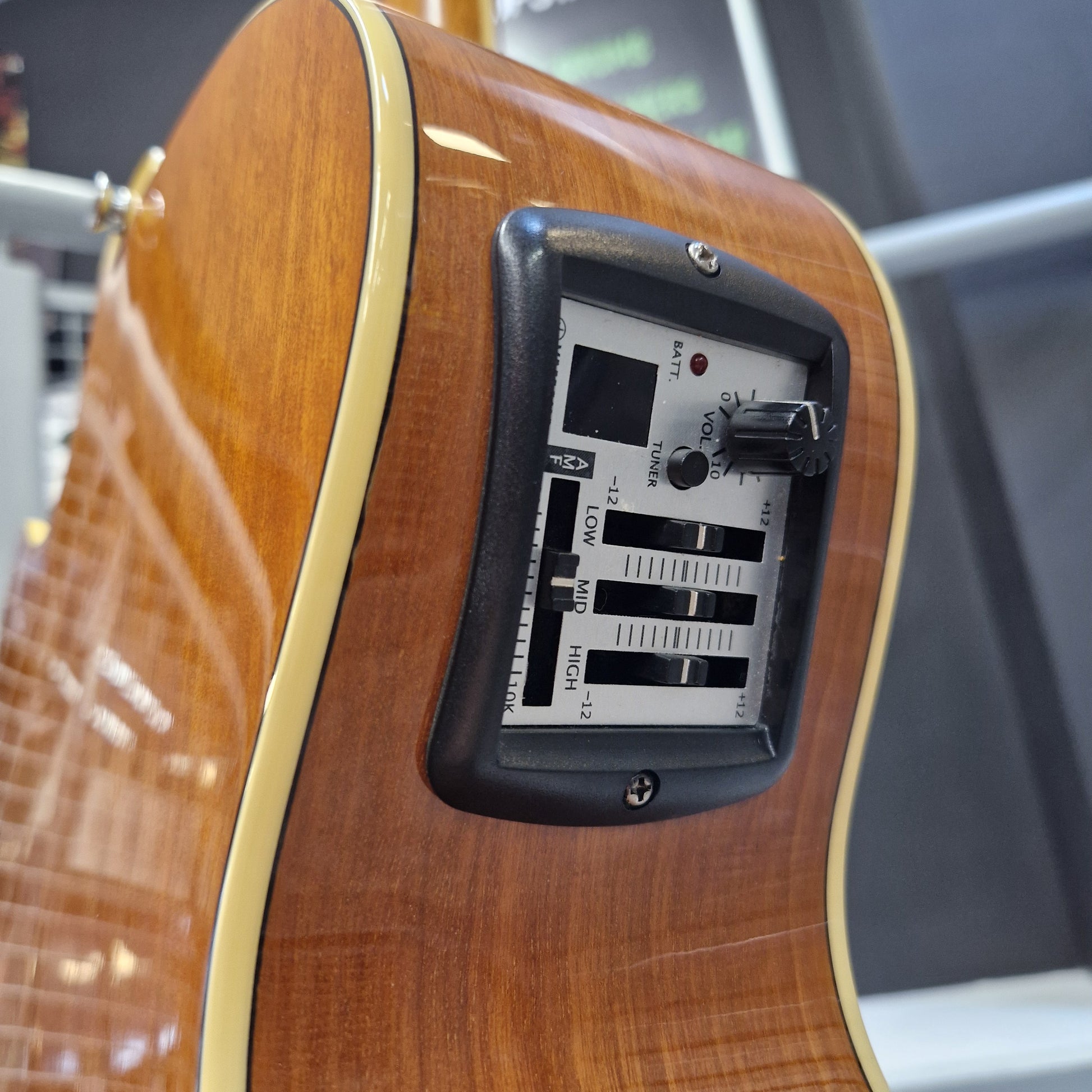 Pre-Owned Yamaha CPX700 Close-up of the back of a wooden electric guitar showing the control panel with volume, tune, low, mid, and high volume sliders.