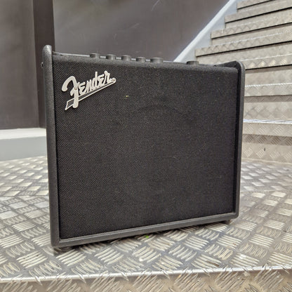 Pre-Owned Fender A Fender guitar amplifier speaker cabinet with a black textured fabric grille and the silver Fender logo, photographed on a diamond-plate metal surface.