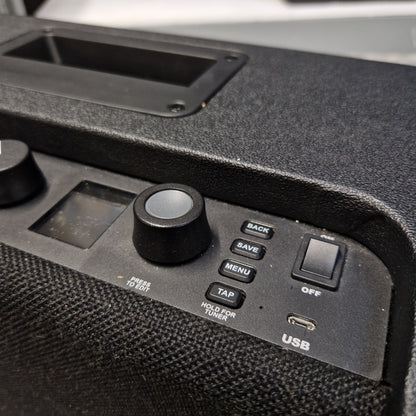 Pre-Owned Fender Close-up of a black electronic control panel with buttons, a rotary knob, a small display, and a textured speaker grille.