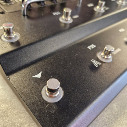 Pre-Owned Line 6 Close-up of a black metal guitar effects pedal with silver knobs and white markings, showing a footswitch and control dials.