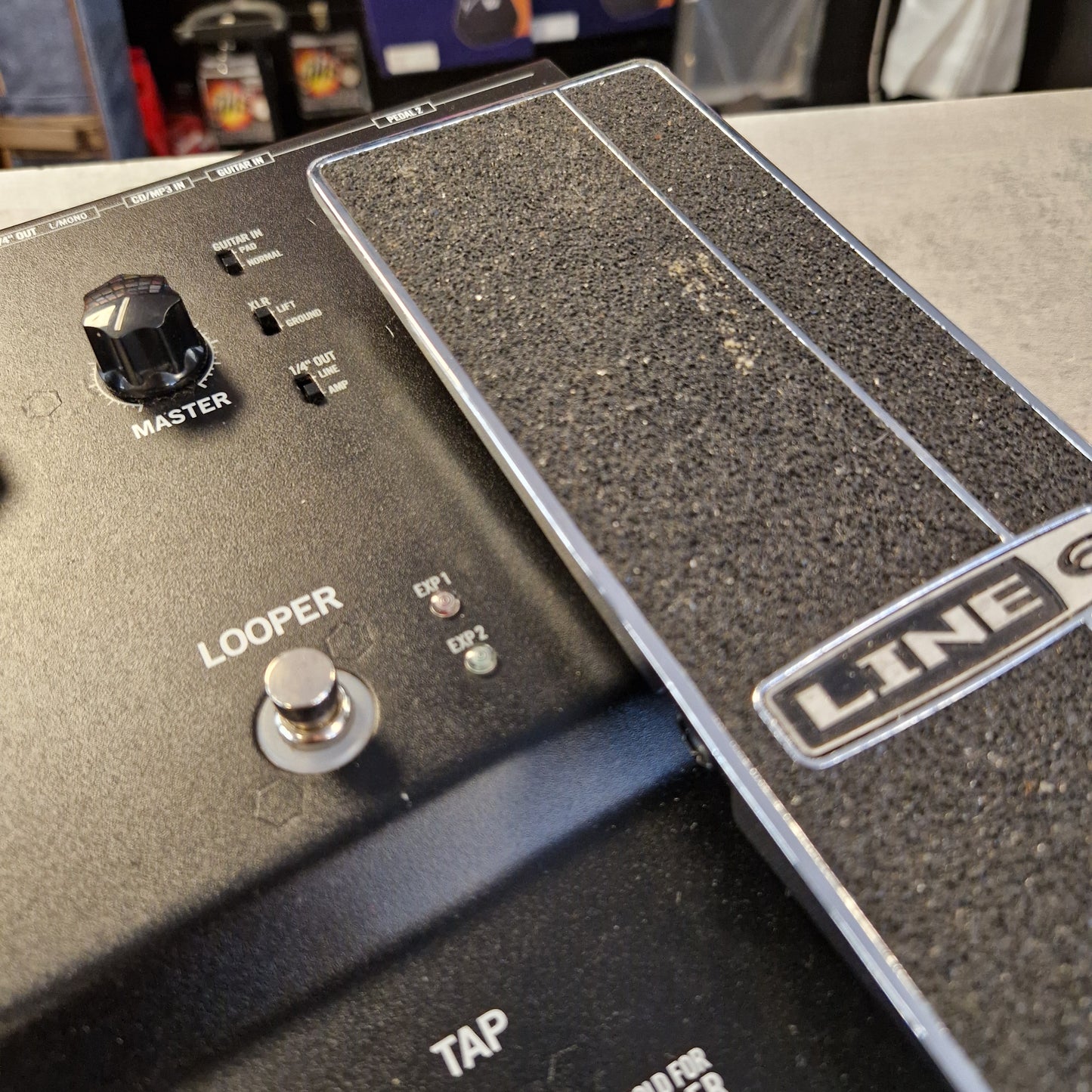 Pre-Owned Line 6 Close-up of a Line 6 Looper pedal guitar effect module, showing the textured black footplate, white brand logo, master knob, tap switch, and loop jack connector.