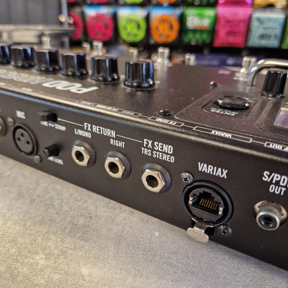 Pre-Owned Line 6 Close-up of the rear panel of a black audio effects processor or mixer, showing input jacks including S/PD OUT, VARIAX, FX SEND, FX RETURN, and a 1/4-inch input, with colorful effect modules blurred in the background.