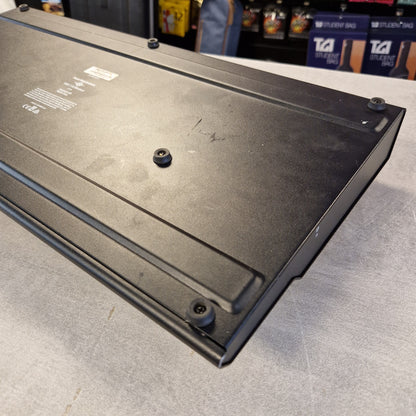 Pre-Owned Line 6 A black metal electronic component or enclosure panel with screws and printed technical labels, photographed on a gray floor with store shelves visible in the background.