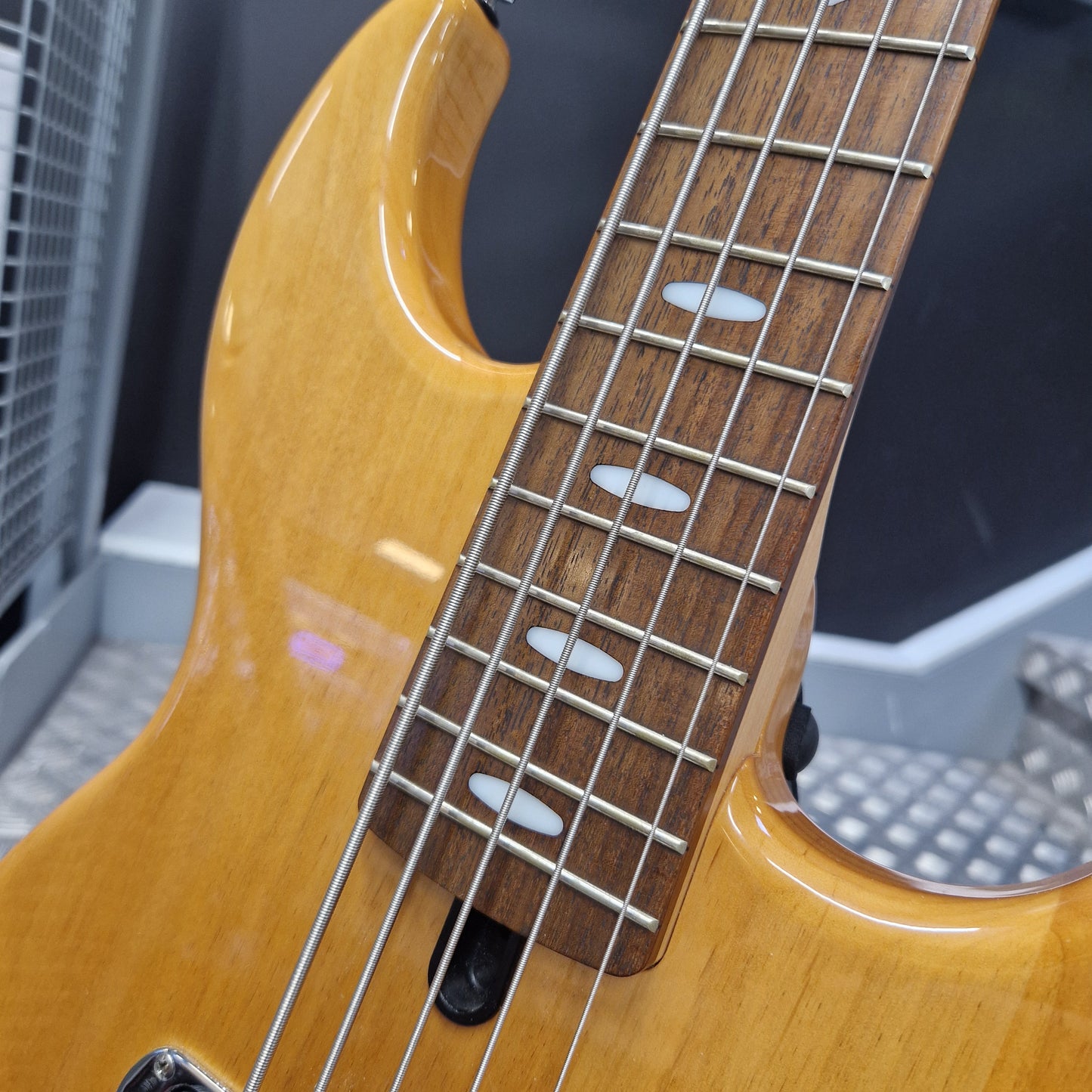 Pre-Owned Yamaha BB615 Close-up of a natural wood bass guitar body and fretboard with silver metal strings and white oval inlays.