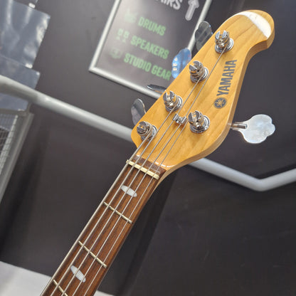 Pre-Owned Yamaha BB615 Close-up of a Yamaha bass guitar headstock and upper neck, showing the Yamaha logo, four tuning pegs, and the fretboard in a shop setting.