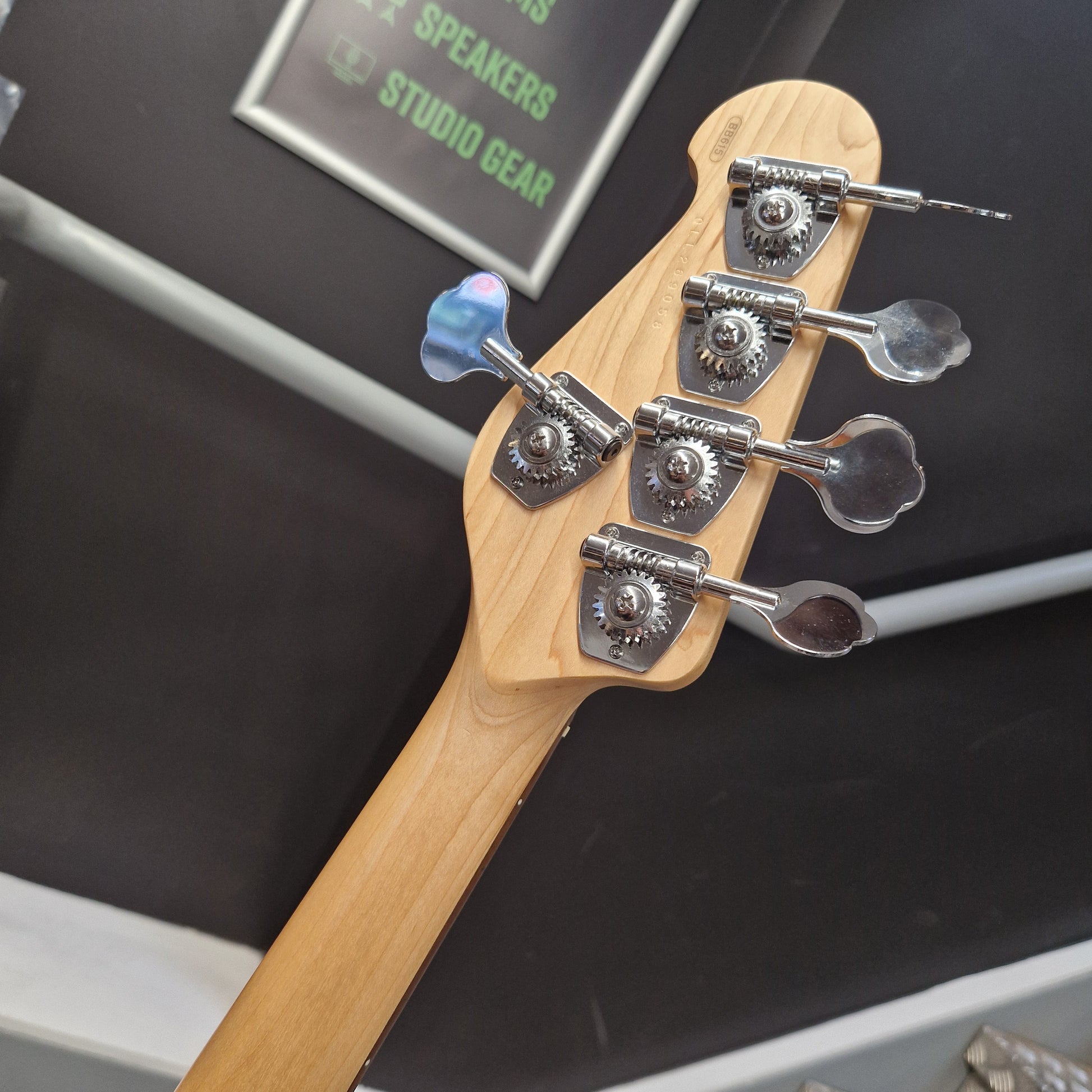 Pre-Owned Yamaha BB615 Close-up of the headstock of a bass guitar, showing a light natural wood neck, four silver tuning machines, and a blue-and-white rainbow sticker on the tuning peg.