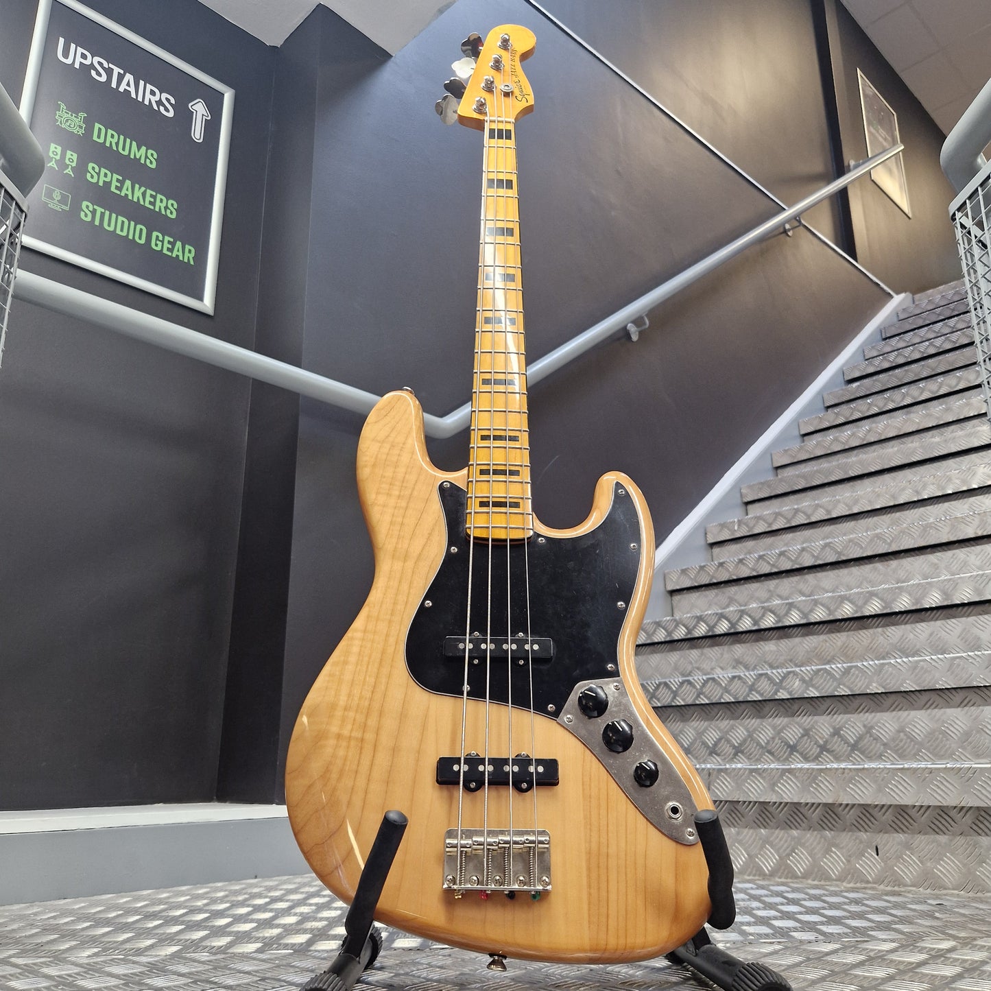 Pre-Owned Squier bass in natural finish on a staircase