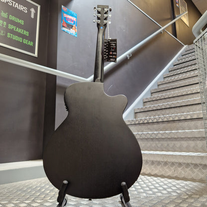 Pre-Owned Tanglewood TWBBSFCELH A black electric guitar body and neck are shown hanging on a display stand inside a store or showroom, with metal shelving and a sign visible in the background.