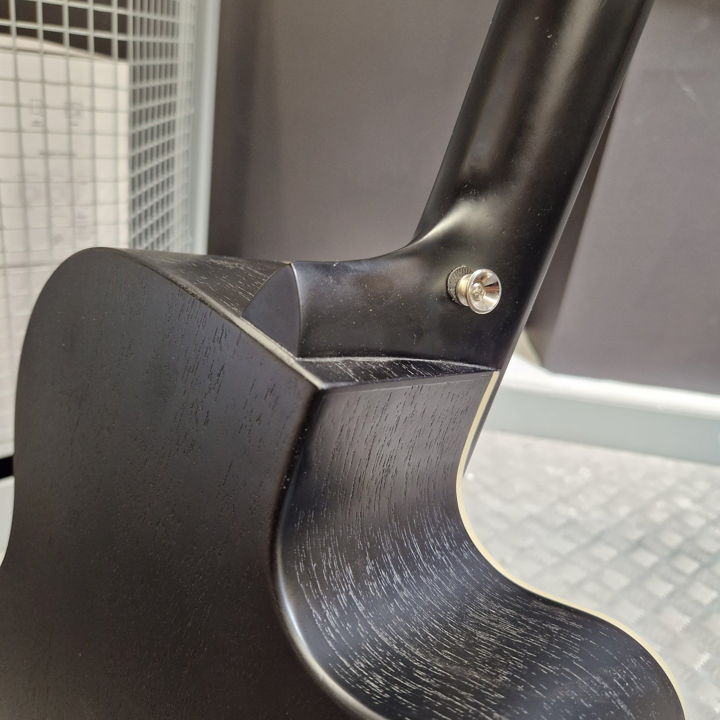 Pre-Owned Tanglewood TWBBSFCELH Close-up detail of a black wooden instrument body joint with a visible silver screw fastener, showing the wood grain and finish.