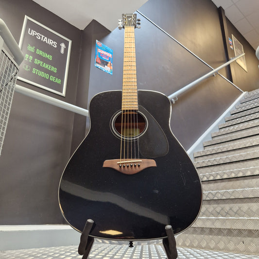 Pre-Owned Yamaha FG800 A black acoustic guitar with a natural wood neck and headstock, displayed on a stand inside a store or studio.
