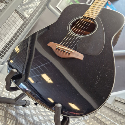 Pre-Owned Yamaha FG800 Close-up of the side of a black acoustic guitar resting on a stand, showing the glossy finish, sound hole, bridge, and part of the neck.