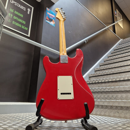 Pre-Owned Squier MIK 1992 A red electric guitar shown from the back, hanging against a textured wall in an indoor showroom or studio space.