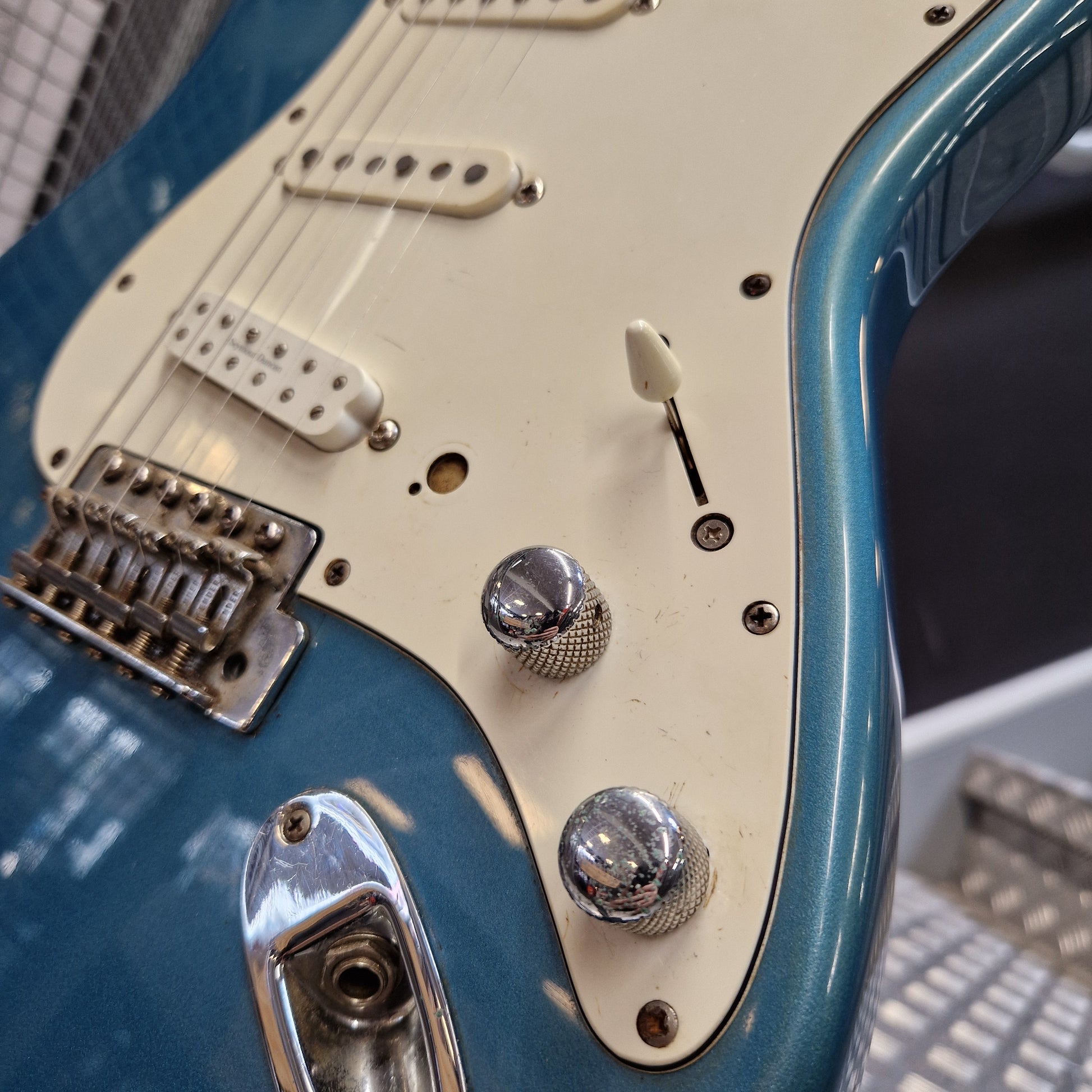 Pre-Owned Fender Mexican Stratocaster 1993 Electric - Lake Placid Blue Close-up of a blue electric guitar body with a cream pickguard, chrome control knobs, and a bridge, photographed indoors with a blurred background.