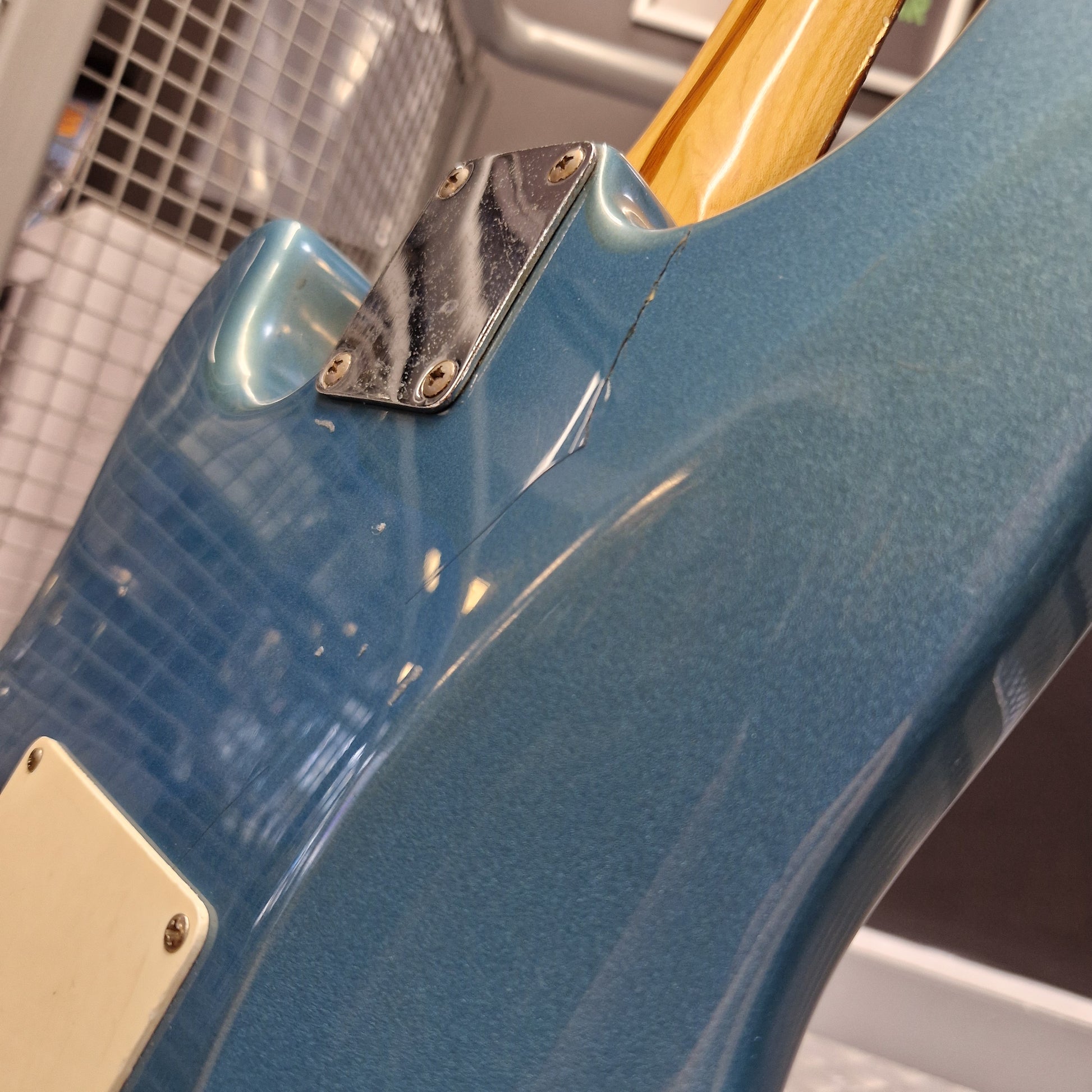 Pre-Owned Fender Mexican Stratocaster 1993 Electric - Lake Placid Blue Close-up of the rear side of an electric guitar body in a metallic blue finish, showing the tailpiece, pickups, and part of the light wood neck.