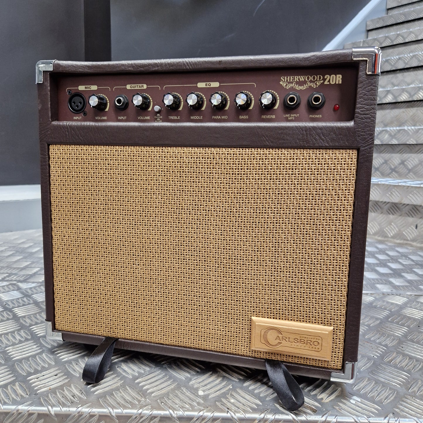 Pre-Owned Carlsbro Sherwood 20R A small guitar amplifier with a dark brown faux-leather front, a tan woven grille, and a gold-toned 'Gibson' logo badge on the upper right. The left side features a control panel with multiple knobs and jacks.