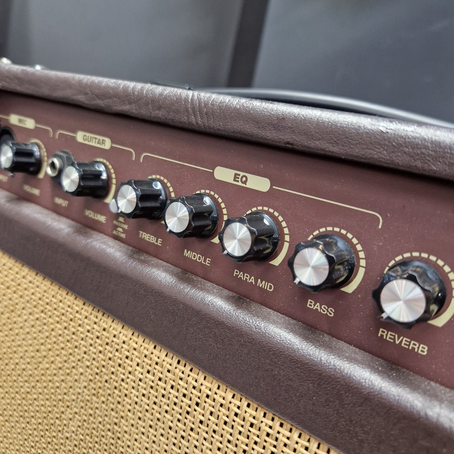 Pre-Owned Carlsbro Sherwood 20R Close-up of a vintage-style guitar or amplifier control panel with brown leatherette trim, black knobs with silver centers, and a beige woven grille.