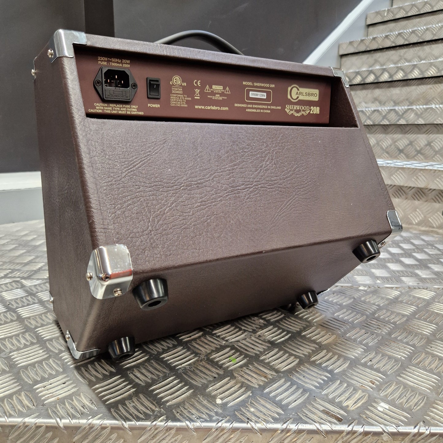 Pre-Owned Carlsbro Sherwood 20R A brown textured guitar amplifier head with a side panel showing controls and an input jack, photographed on a diamond plate metal surface.