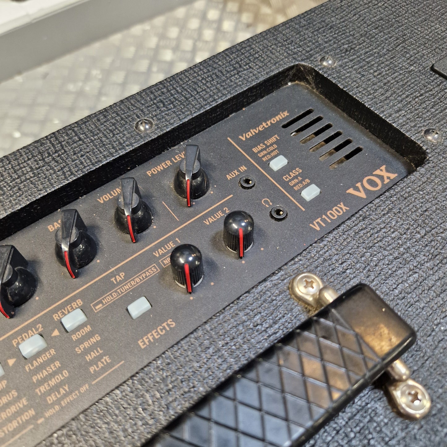 Pre-Owned Vox VT100X Close-up of the control panel of a Vox VT100X guitar amplifier, showing black knobs with red accents, white switches, and gold lettering on a textured black cabinet.