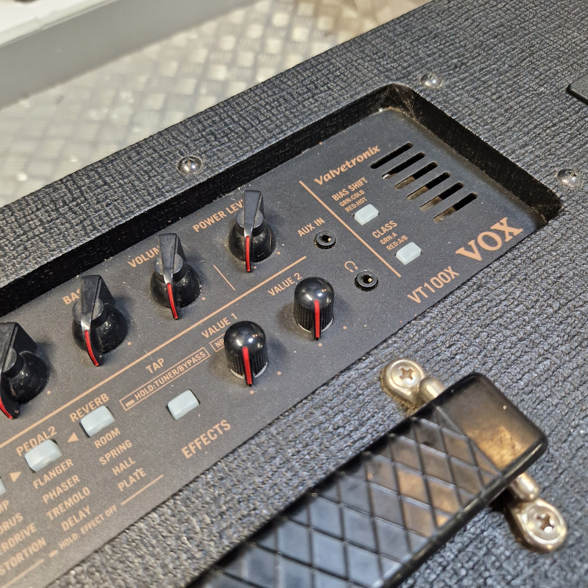 Pre-Owned Vox VT100X Close-up of the control panel of a Vox VT100X guitar amplifier, showing black knobs with red accents, white switches, and gold lettering on a textured black cabinet.