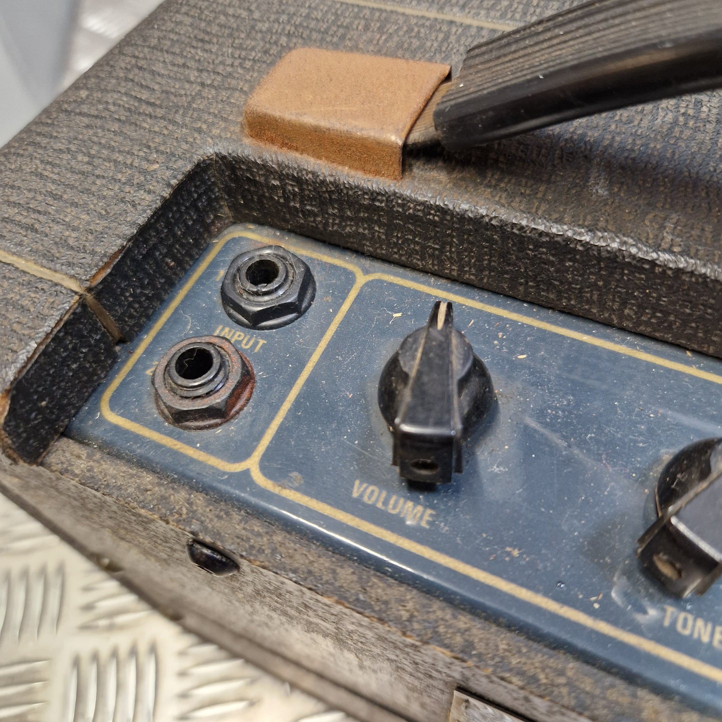 Pre-Owned Vox Escort Close-up of a vintage guitar amplifier or speaker cabinet control panel with a black foot pedal resting on top, showing input and volume knobs on a blue faceplate.