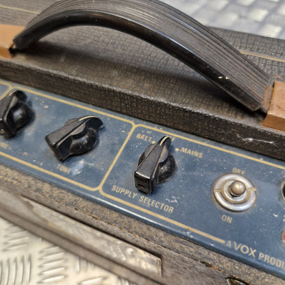 Pre-Owned Vox Escort Close-up of the control panel of a vintage Vox amplifier, showing black knobs, a blue faceplate with gold lettering, and a black handle on a weathered wooden body.