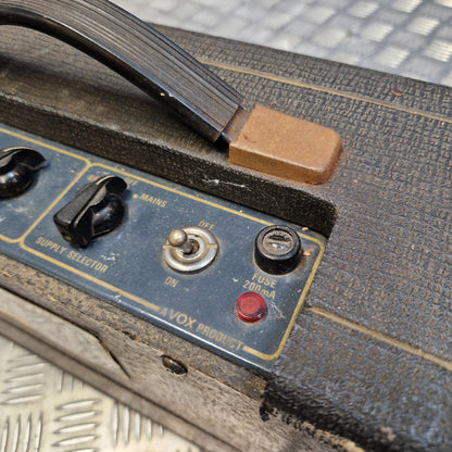 Pre-Owned Vox Escort Close-up of a vintage Vox Products amplifier control panel with black knobs, a silver switch, and a red fuse indicator on a dark textured surface.