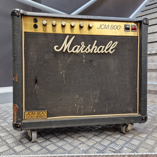 Pre-Owned Marshall JCM 800 A vintage Marshall JCM 800 LF0D Series guitar amplifier head, featuring a black textured grille cloth with a cream-colored Marshall logo, gold trim, and control knobs on the left side, resting on a diamond plate metal surface.