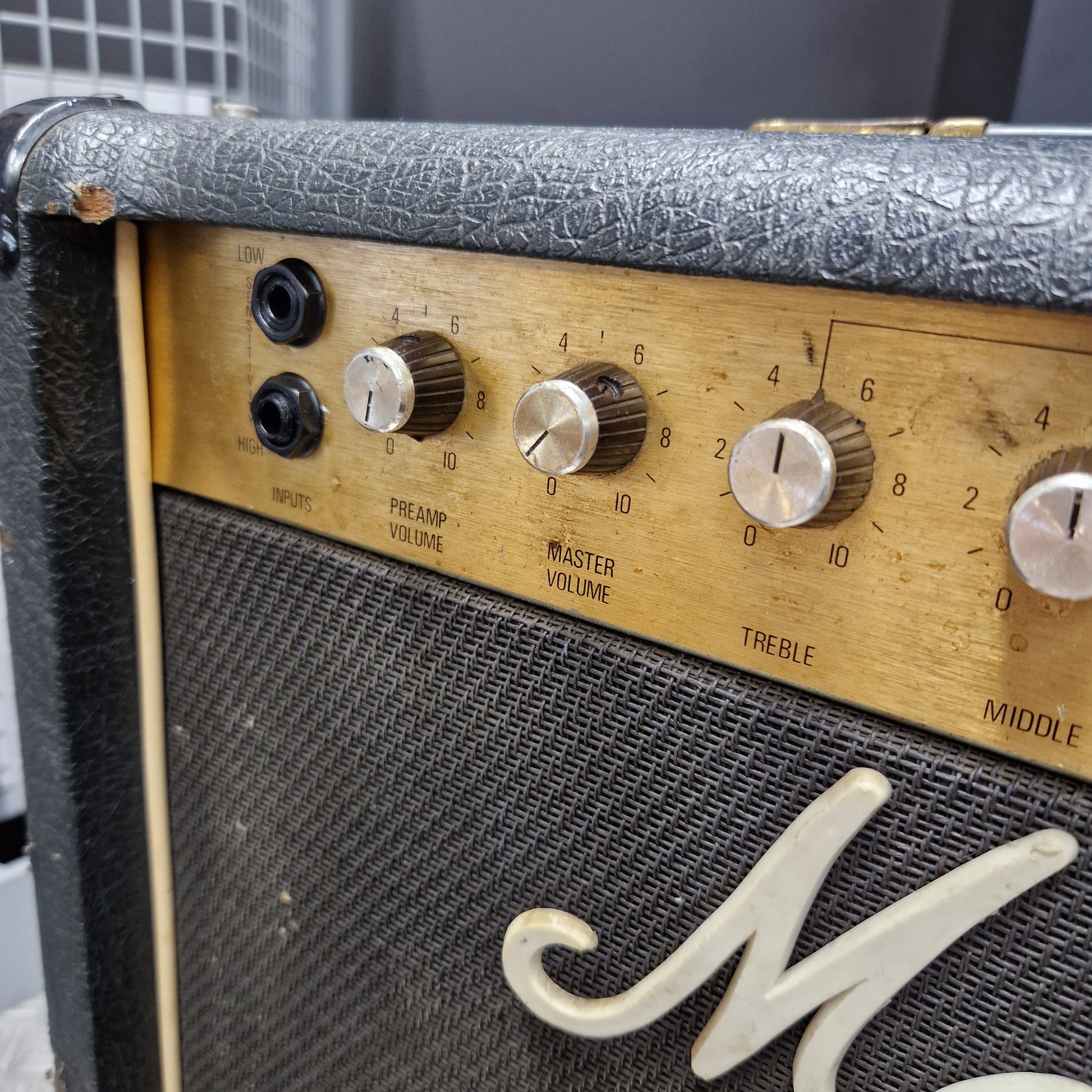 Pre-Owned Marshall JCM 800 Close-up of a vintage Marshall guitar amplifier showing the front grille, control knobs, and part of the white Marshall logo on a wooden panel.