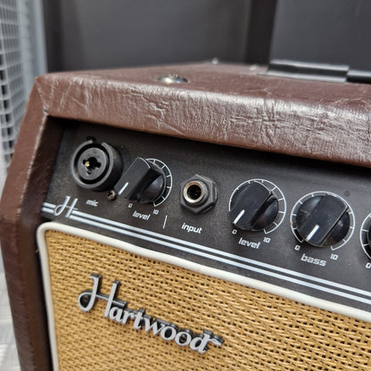 Pre-Owned Hartwood HW-AA-30 Close-up of a vintage-style guitar amplifier showing the brown textured side cover, black control knobs, white trim, and tan mesh grille with a silver Hartwood logo.