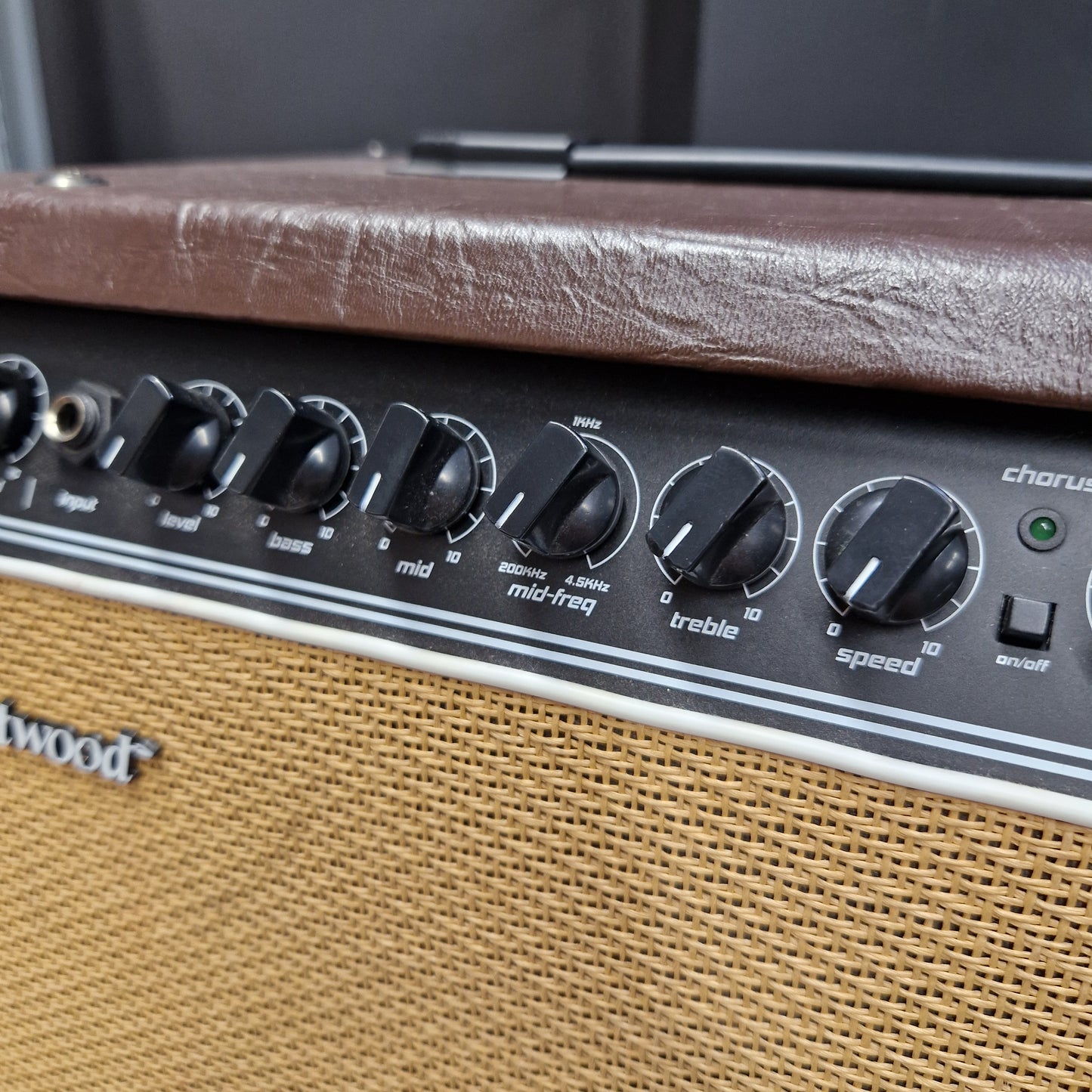Pre-Owned Hartwood HW-AA-30 Close-up of a vintage guitar amplifier showing the control panel with black knobs, a brown leather-covered edge, and a tan mesh grille.