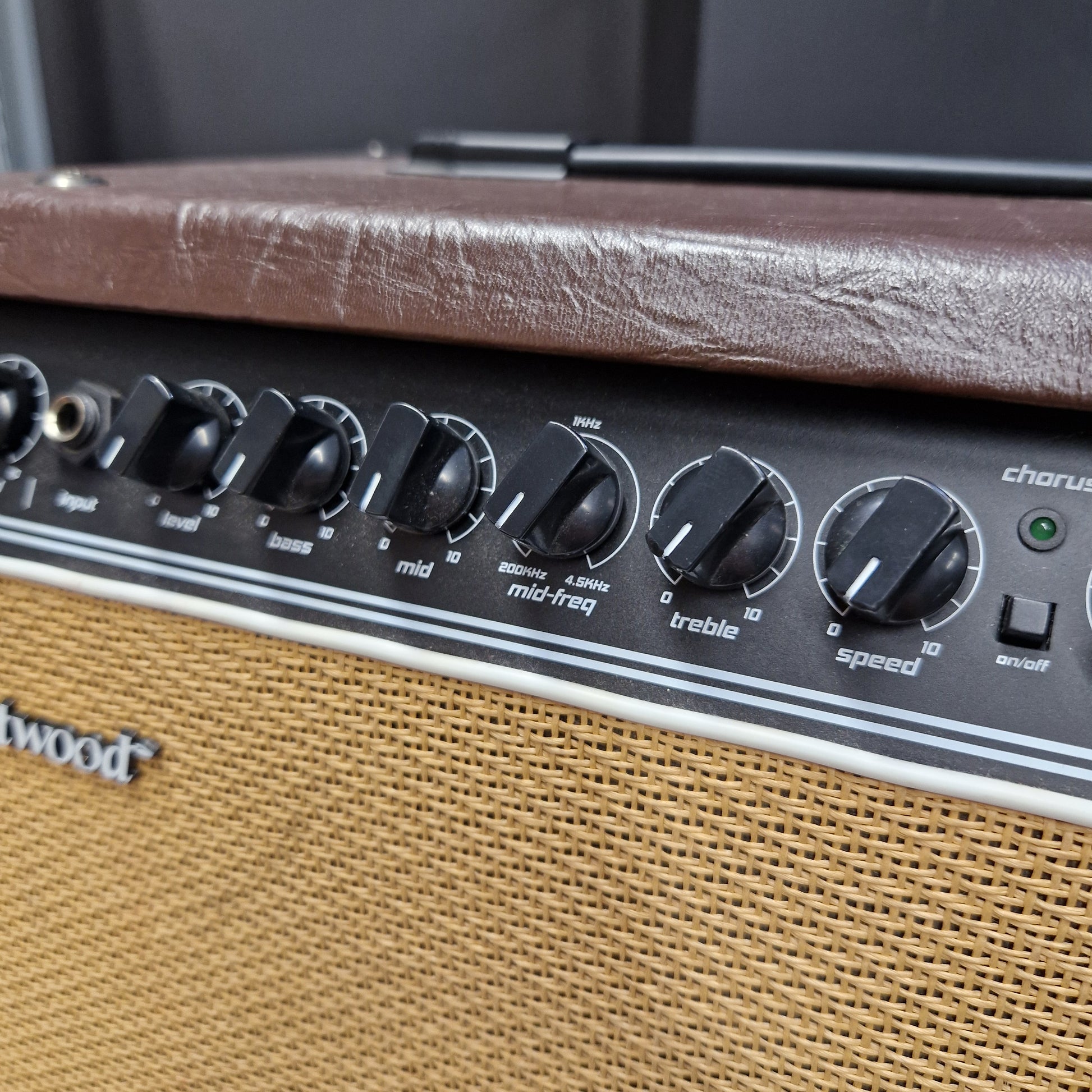 Pre-Owned Hartwood HW-AA-30 Close-up of a vintage guitar amplifier showing the control panel with black knobs, a brown leather-covered edge, and a tan mesh grille.